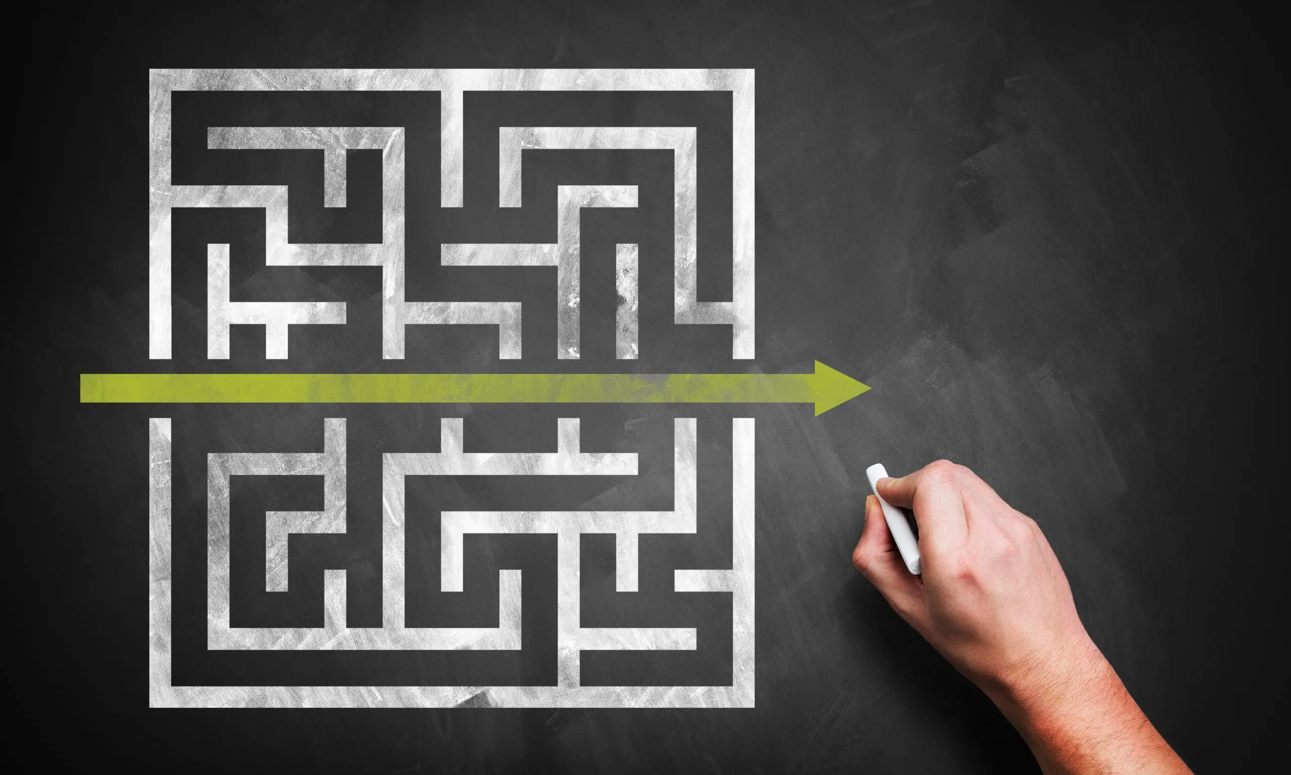 A hand draws a straight line through the center of a maze.
