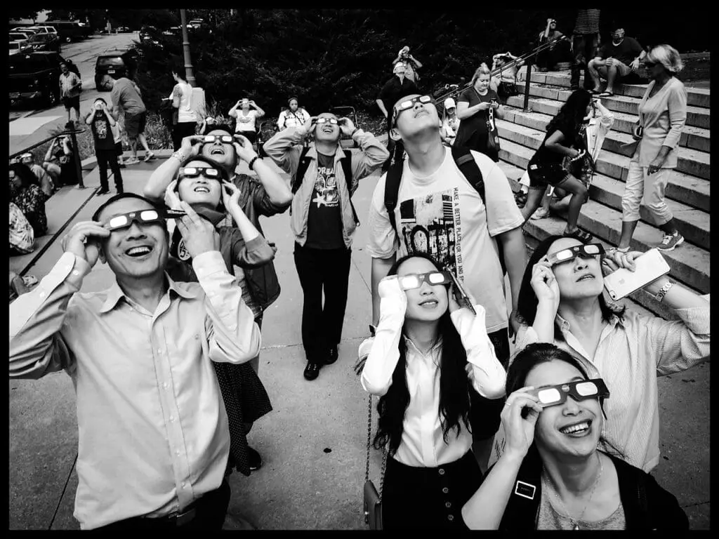 A crowd looking at a solar eclipse through eclipse glasses.