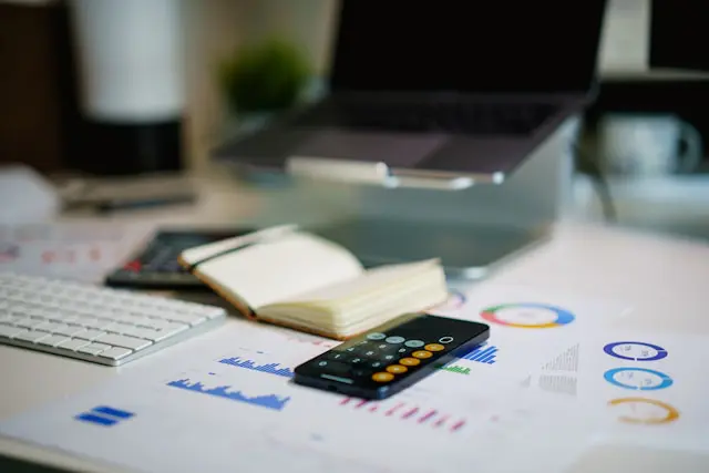 A tabletop covered with papers, a calculator, and a laptop. Planning for financial independence takes care and focus.