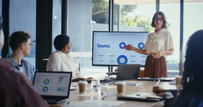 A woman presenting financial stats to a group of people. Talking about planning clients haven't yet considered puts them in a better position. 