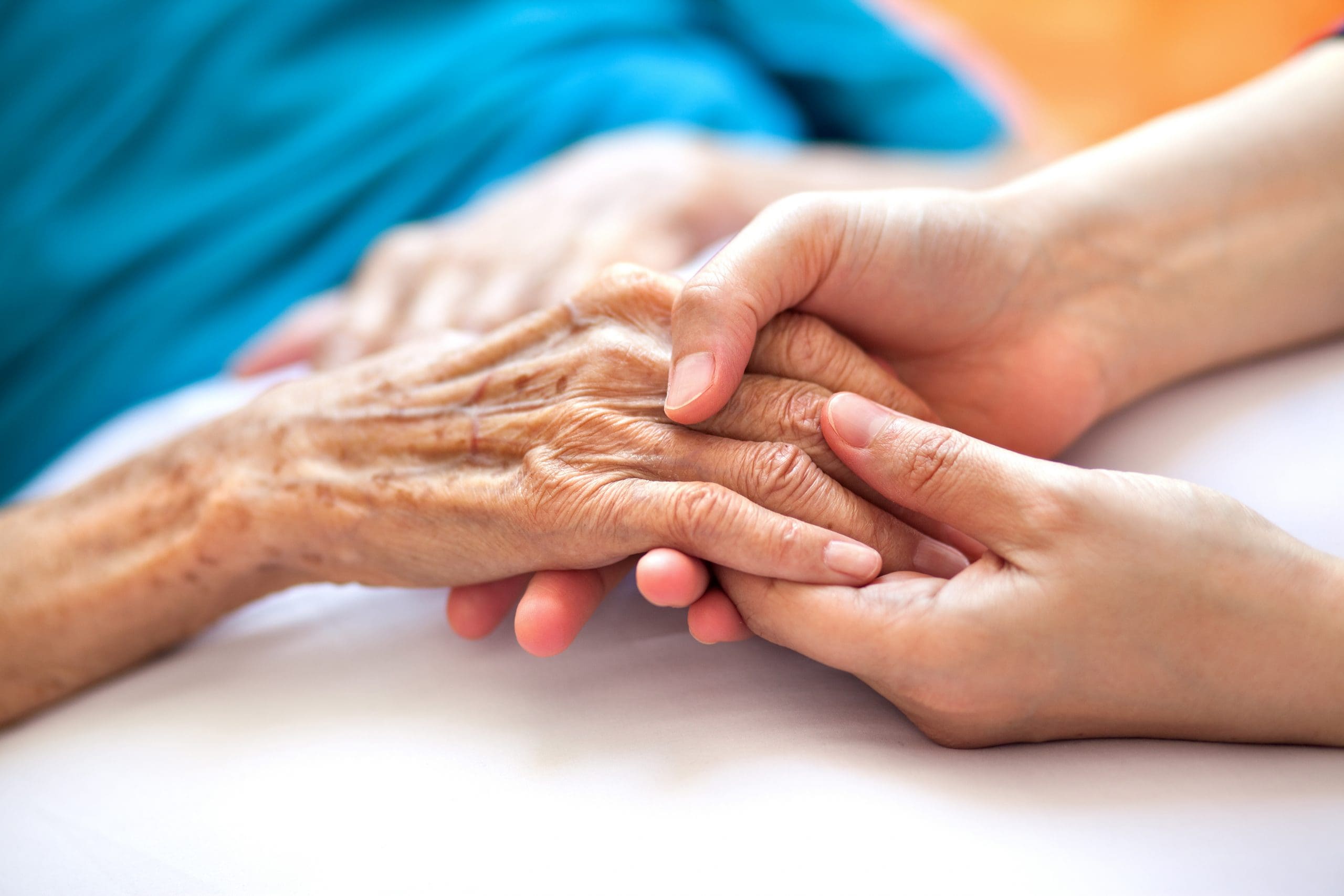 Woman holds hands with her elderly mother.